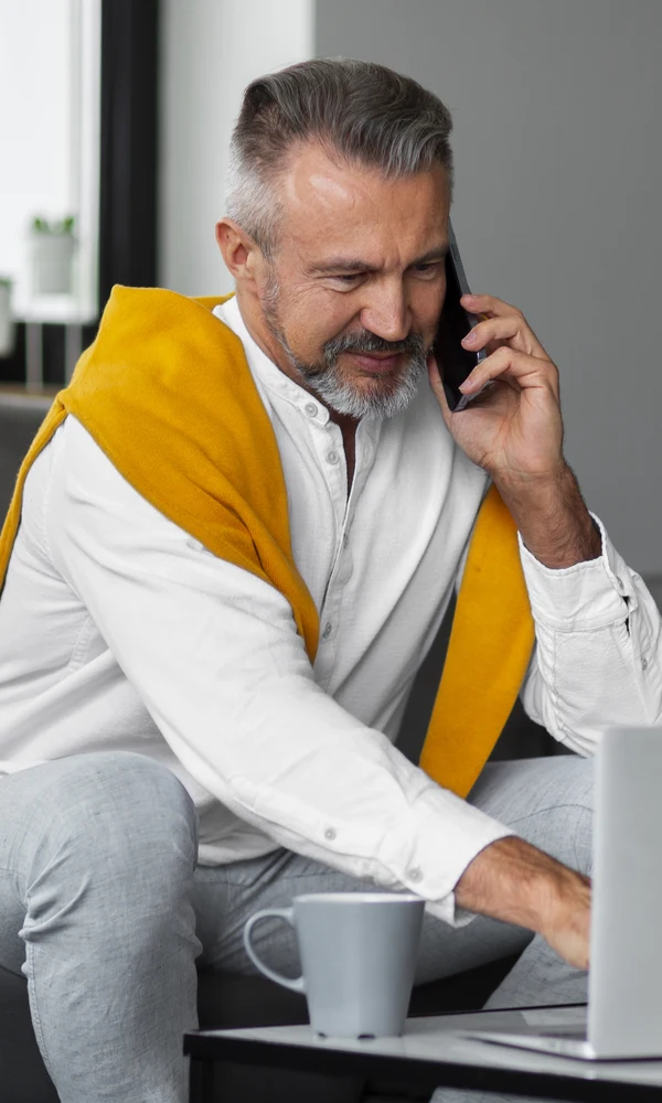 Empresário falando ao telefone enquanto usa o notebook