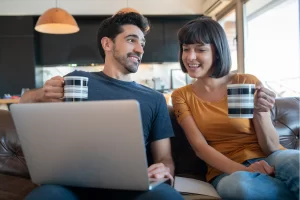 Casal de empreendedores lendo artigo no notebook sobre: Escrituração fiscal digital: o que é, para que serve e como preparar sua empresa.