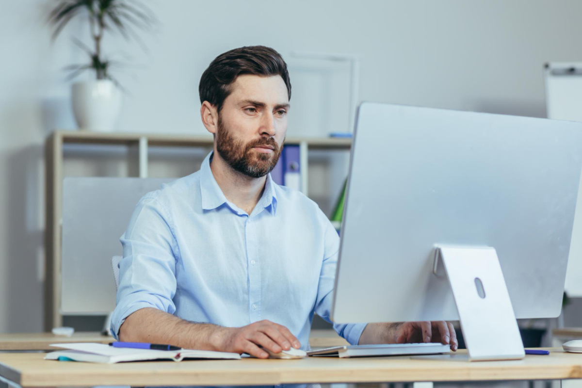 Contador lendo artigo em seu computador sobre: Planejamento tributário para PMEs: como escolher o melhor regime e pagar menos imposto.