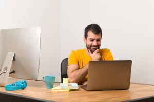 Empreendedor lendo artigo no seu notebook: Como emitir nota fiscal para reembolso de despesas: quais regras sua empresa precisa seguir.
