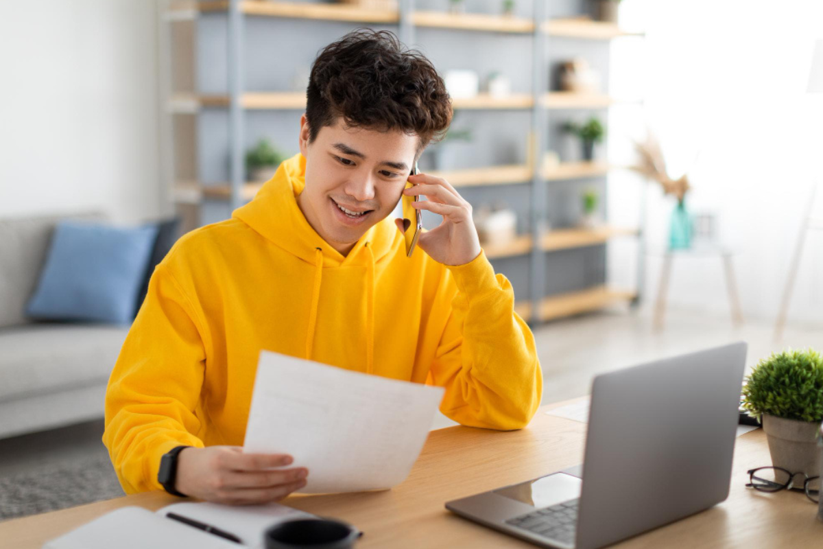 Homem em frente a um notebook com um documento na mão, que contém informações sobre como cancelar uma nota fiscal eletrônica, prazos, regras e implicações legais.