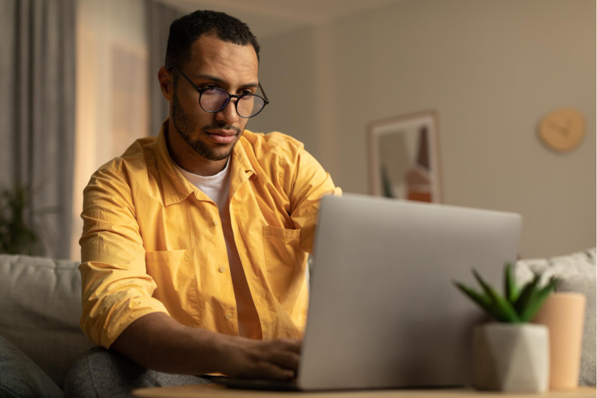 Homem sentado mexendo em um notebook em ambiente de escritório representando: CFOP 6108: guia da devolução de venda de bem do ativo imobilizado.