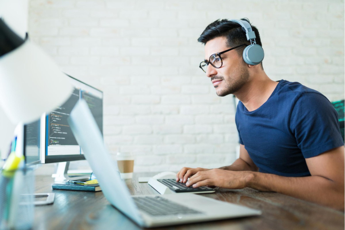 Homem sentado em ambiente de escritório usando um notebook e um computador sobre uma mesa referenciando CFOP 5949: tudo sobre outra saída de mercadoria.