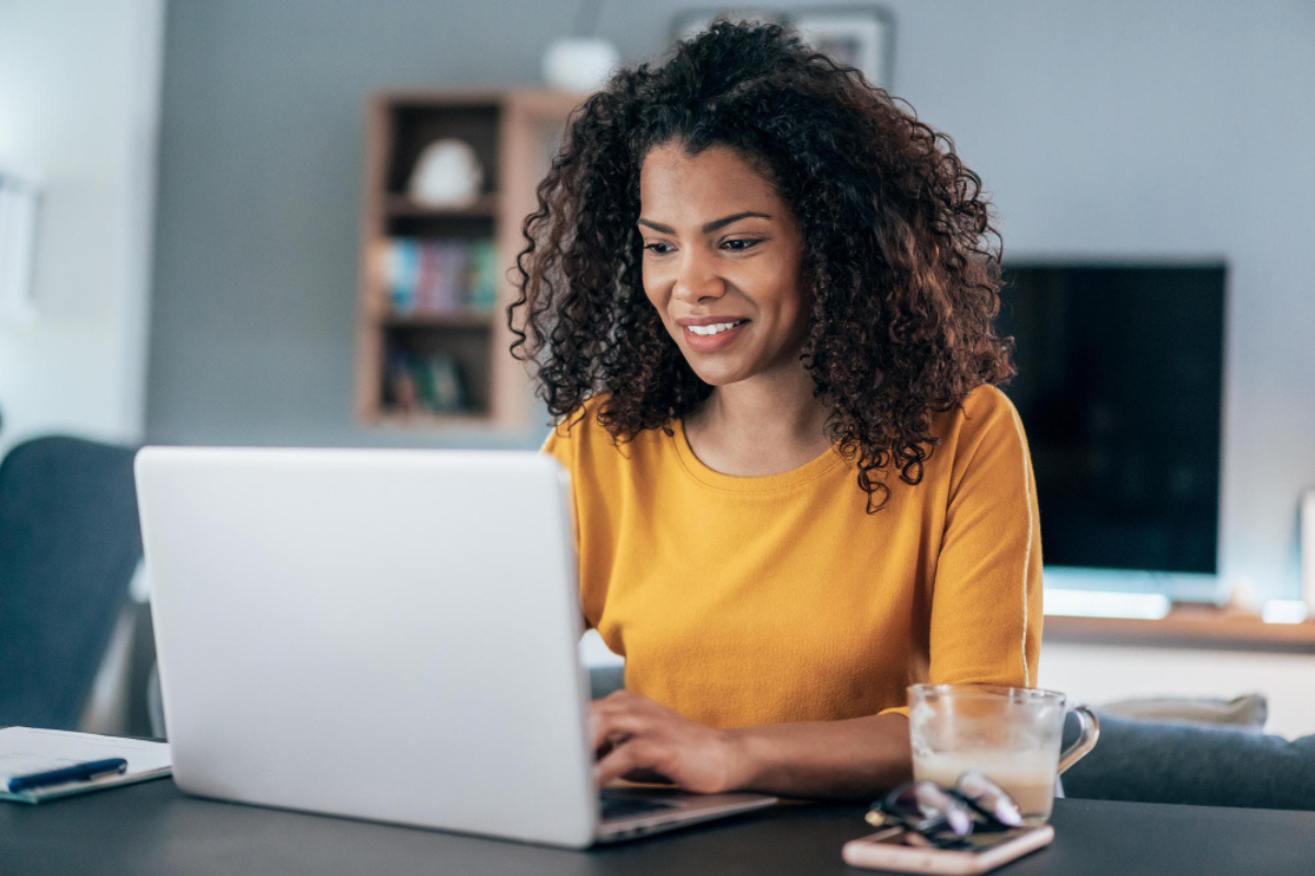 Mulher empresária sentada mexendo em um notebook sobre uma mesa em ambiente de escritório representando: CFOP 1202: guia completo da devolução de venda de mercadoria.
