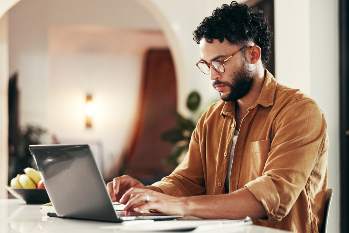 Homem sentado usando notebook sobre uma mesa em ambiente de escritório representando: CFOP 5411: guia da devolução de compra para comercialização em operação com mercadoria sujeita ao regime de substituição tributária.