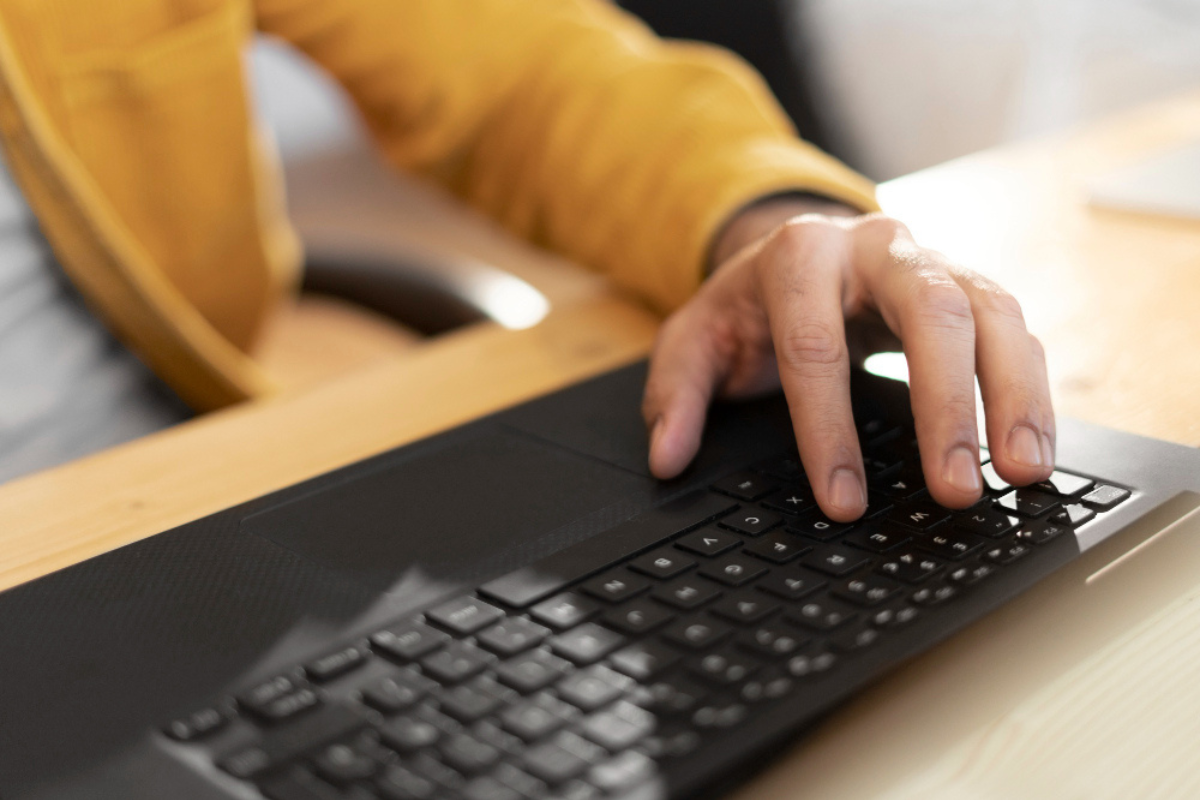 Homem em ambiente de escritório sentado usando um notebook sobre uma mesa representando: Rejeição 203: emitente não habilitado para emissão de NF-e.