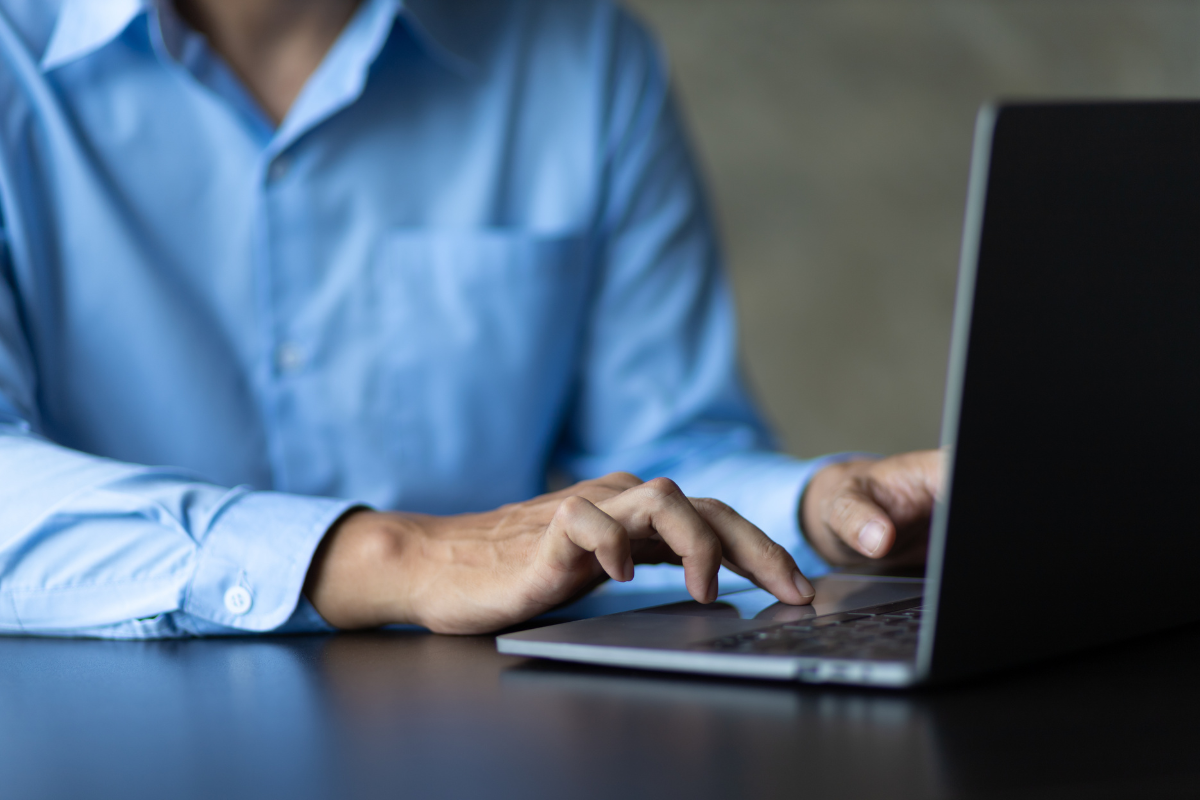 Homem sentado usando notebook sobre uma mesa em ambiente de escritório representando: CFOP 5556: tudo sobre devolução de compra de material de uso ou consumo.