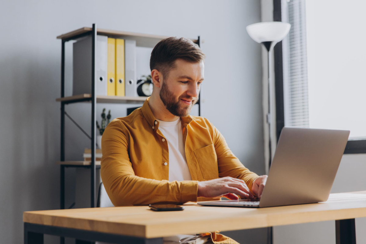 Homem sentado trabalhando em um notebook sobre uma mesa em ambiente de escritório representando: Reforma Tributária: o que você precisa saber para 2026.