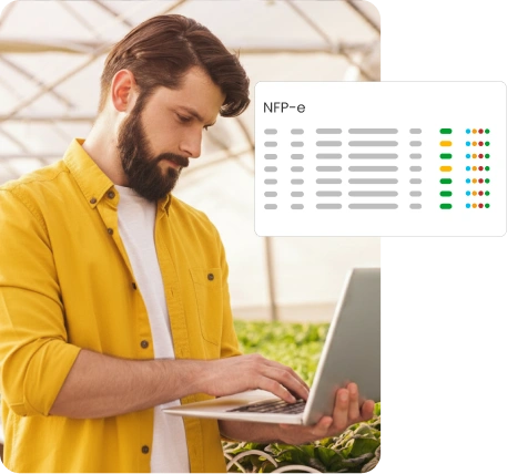 Home em pé usando notebook nas mãos em ambiente de escritório representando: NFP-e - nota fiscal de produtor eletrônica.