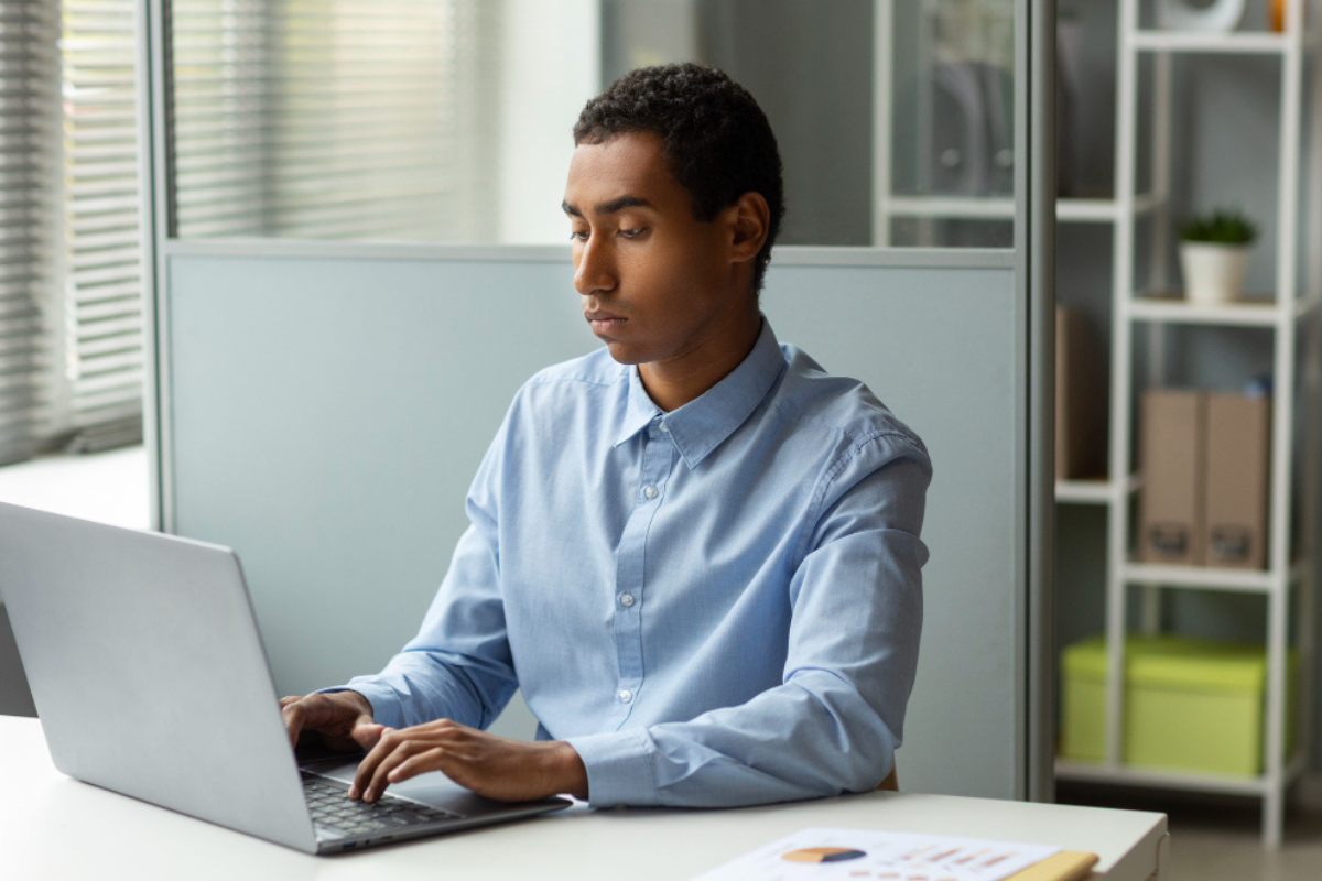 Homem sentado trabalhando em um notebook em ambiente de escritório representando: Repartição tributária: o que é e como funciona no Brasil.