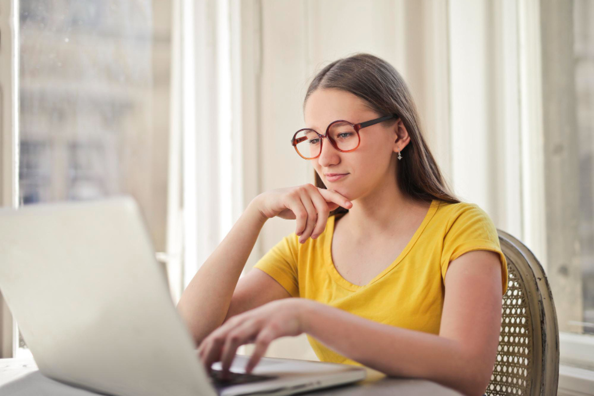 Mulher sentada usando um notebook em ambiente de escritório representando: Obrigações acessórias: o que muda e quando muda com a Reforma Tributária.