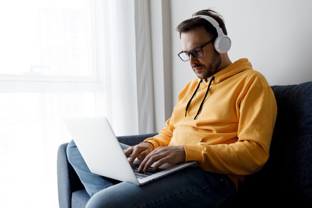 Homem trabalhando em um notebook sentado em um sofá em ambiente home office representando: Como destacar o IBS no XML?