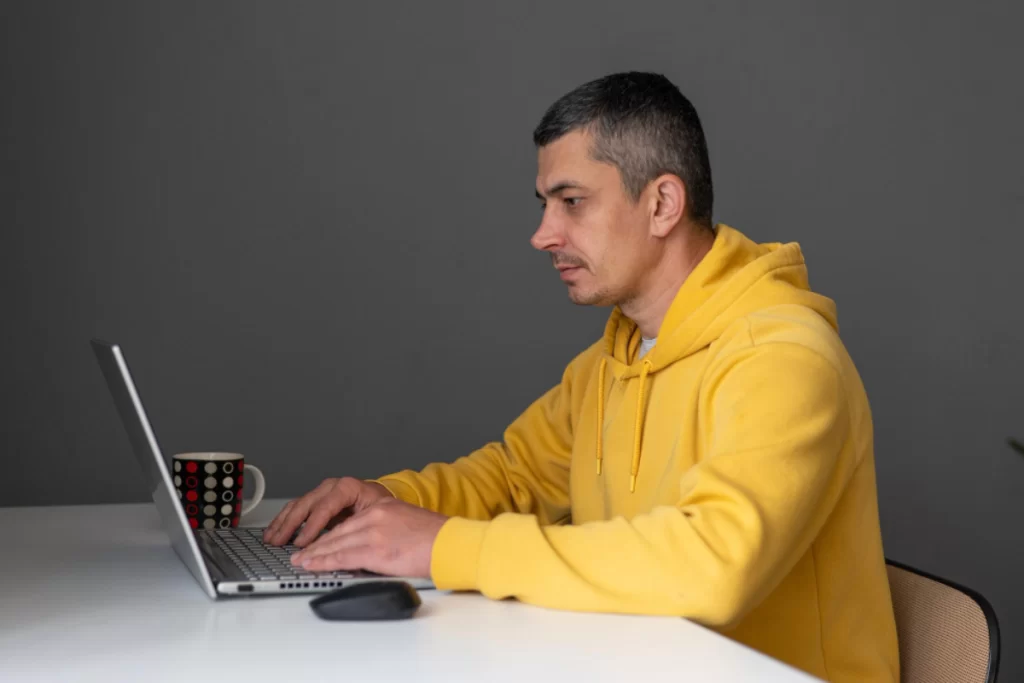 Homem sentado usando notebook sobre uma mesa em ambiente de escritório representando: Como se preparar para a Reforma Tributária em 2026?