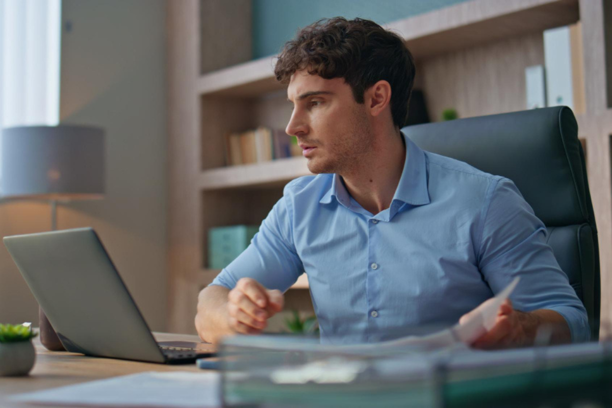 Homem em ambiente de escritório sentado trabalhando em um notebook sobre uma mesa representando: Gestão tributária: o que é e como fazer.