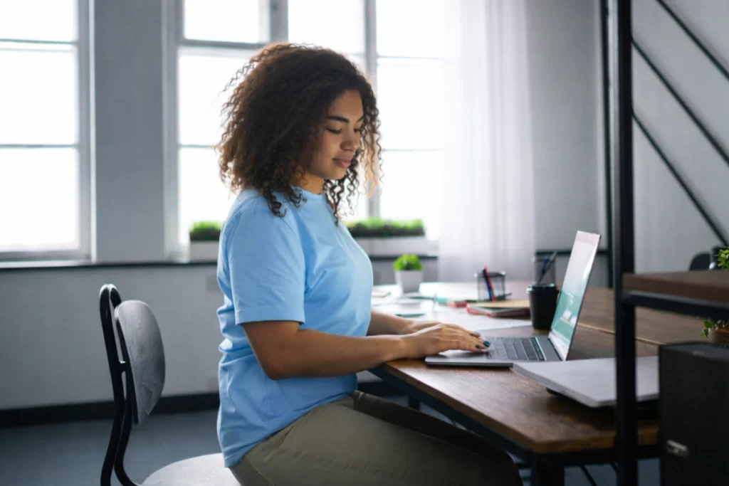 Mulher trabalhando em um notebook sobre uma mesa em ambiente de escritório representando: Rejeição 778: Informado NCM inexistente.