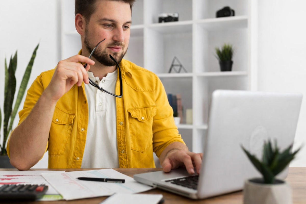 Homem sentado trabalhando em um notebook em ambiente home office representando: Justiça fiscal e fim da insegurança jurídica no novo sistema tributário brasileiro.