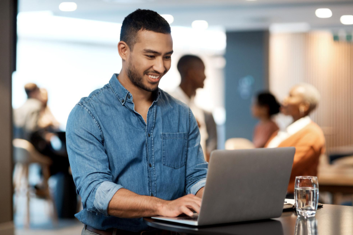 Homem sentado trabalhando em um notebook em ambiente de escritório representando: O Imposto Seletivo muda o XML?