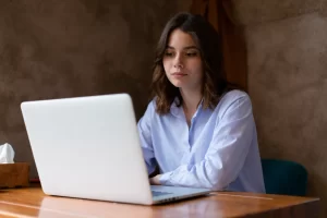 Mulher trabalhando em um notebook sobre uma mesa em ambiente de escritório representando: Escrituração Fiscal: o que muda com a Reforma Tributária?