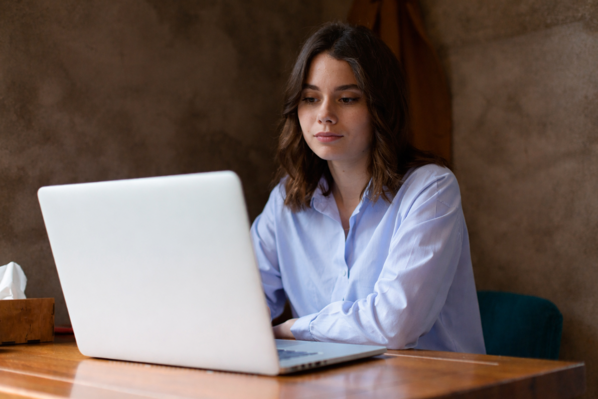 Mulher trabalhando em um notebook sobre uma mesa em ambiente de escritório representando: Escrituração Fiscal: o que muda com a Reforma Tributária?