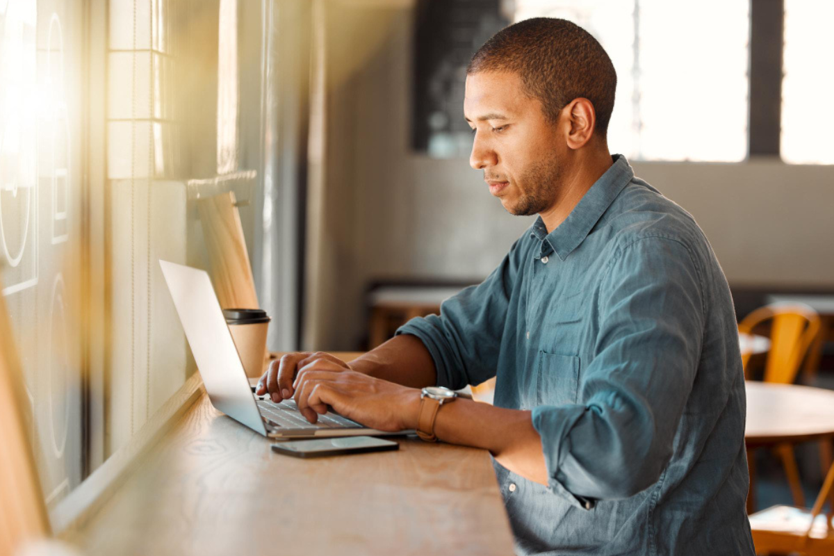 Homem sentado trabalhando em um notebook em ambiente de escritório representando: 5 erros na emissão de notas fiscais durante a transição da Reforma Tributária.