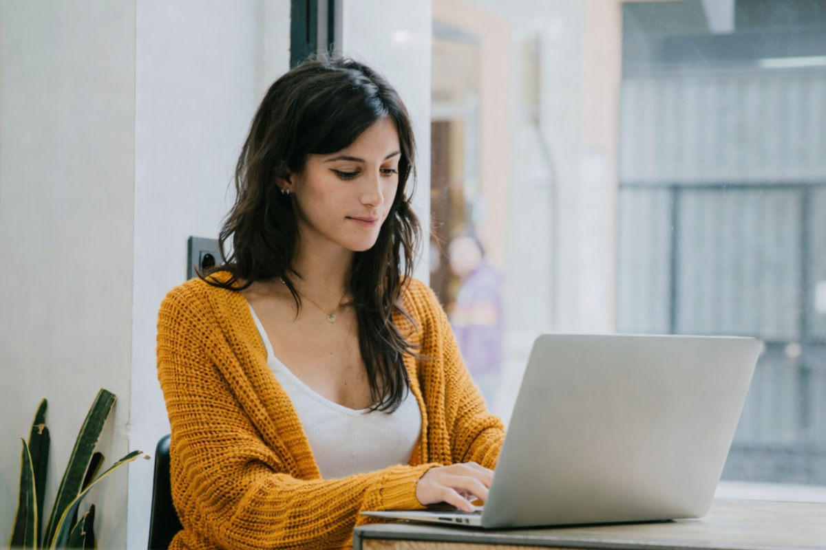 Mulher trabalhando em um notebook sobre uma mesa em ambiente de escritório representando: Guia do CFOP 6914: remessa interestadual para exposição ou feira.