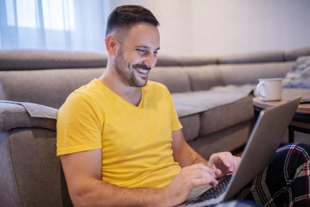 Homem sentado trabalhando em um notebook em ambiente home office representando: O que é e como funciona a apuração assistida da Reforma Tributária.