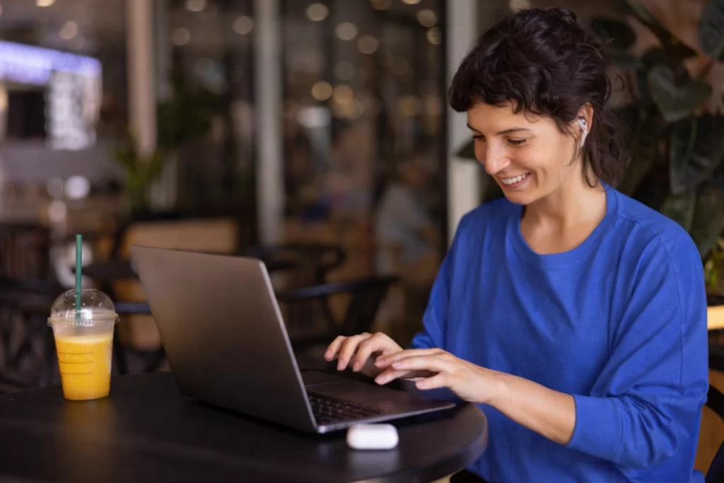 Mulher trabalhando em um notebook sobre uma mesa em ambiente de escritório representando: Como evitar multas de IBS e CBS na Reforma Tributária?