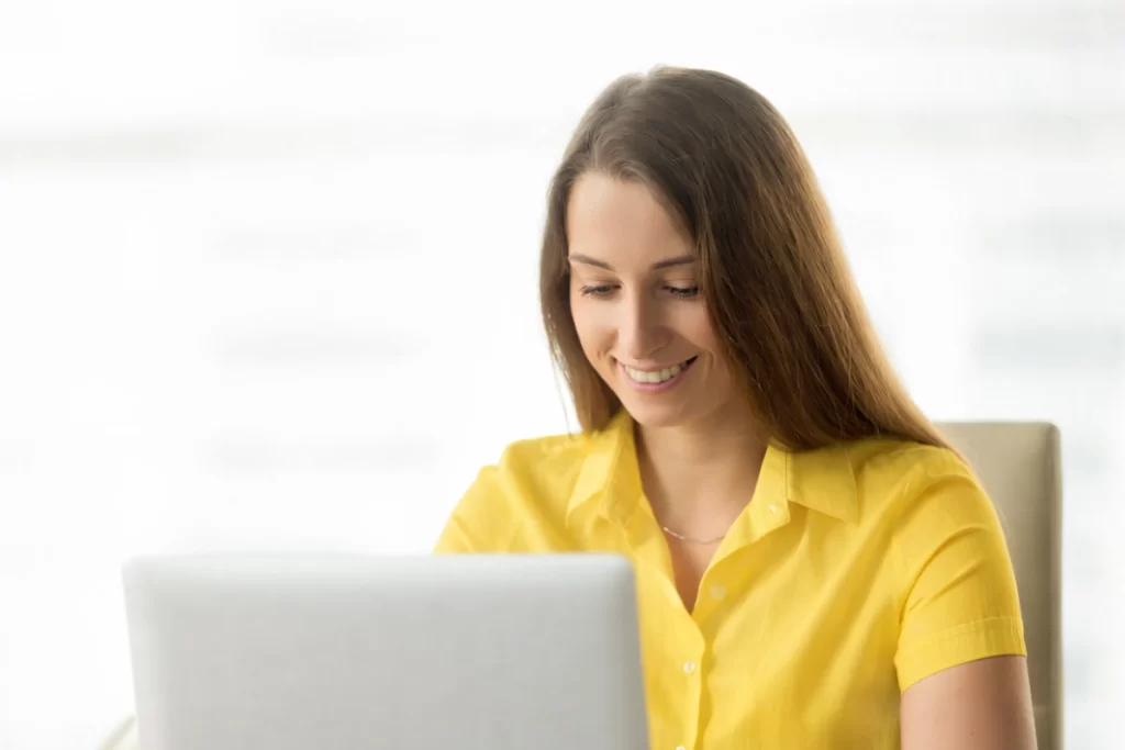 Mulher trabalhando em um notebook sobre uma mesa em ambiente de escritório representando: Apuração Assistida na Reforma Tributária: como a rastreabilidade fiscal afeta o caixa das empresas?