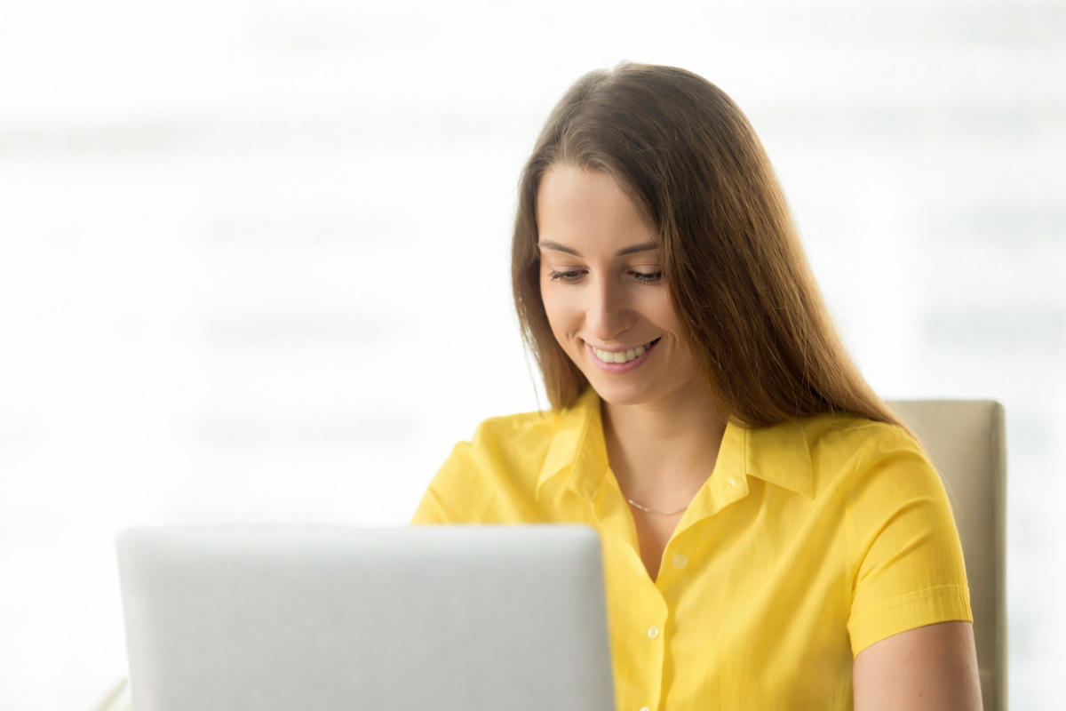 Mulher trabalhando em um notebook sobre uma mesa em ambiente de escritório representando: Apuração Assistida na Reforma Tributária: como a rastreabilidade fiscal afeta o caixa das empresas?