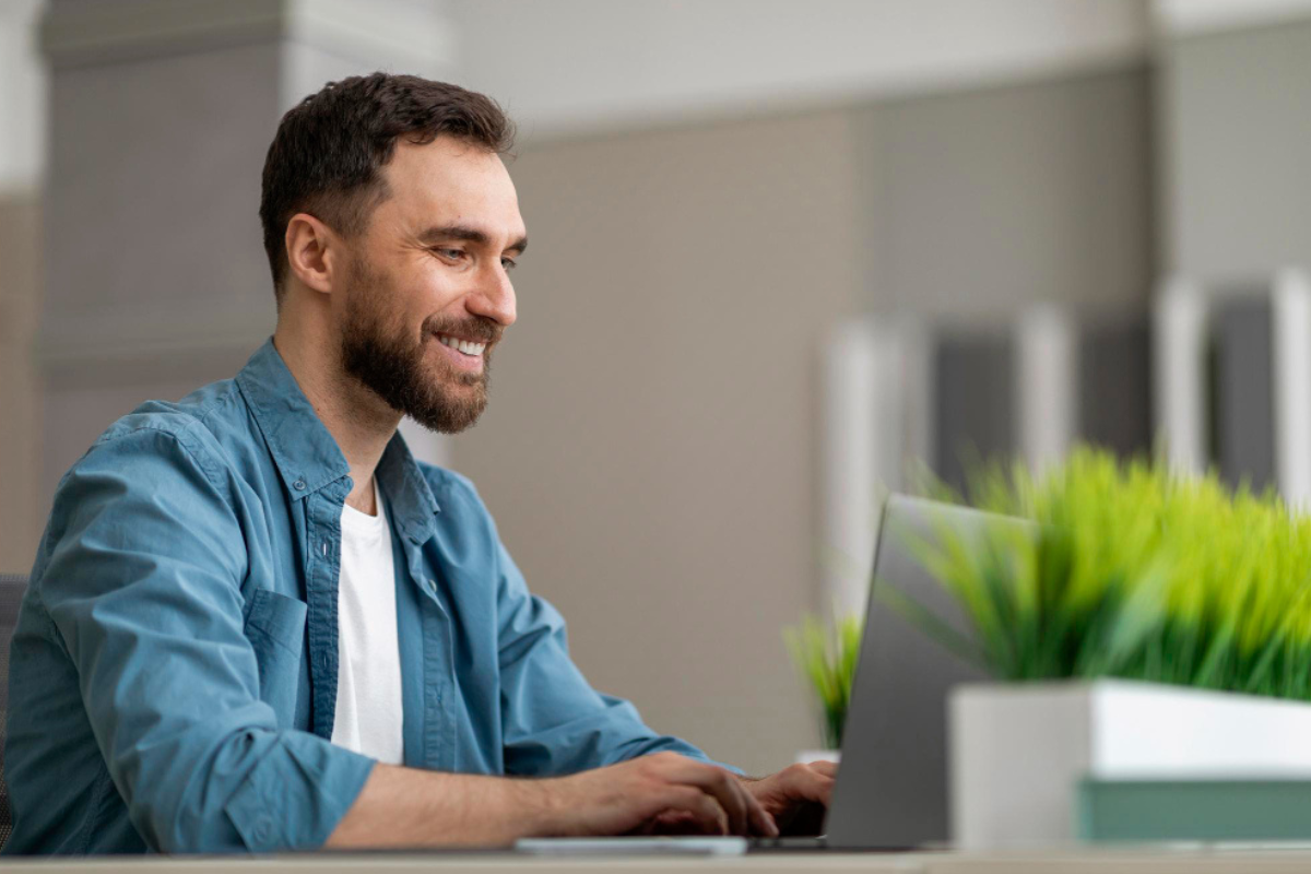 Homem sentado trabalhando em um notebook em ambiente home office representando: Split Payment: o que é, impactos e quando começa a valer?