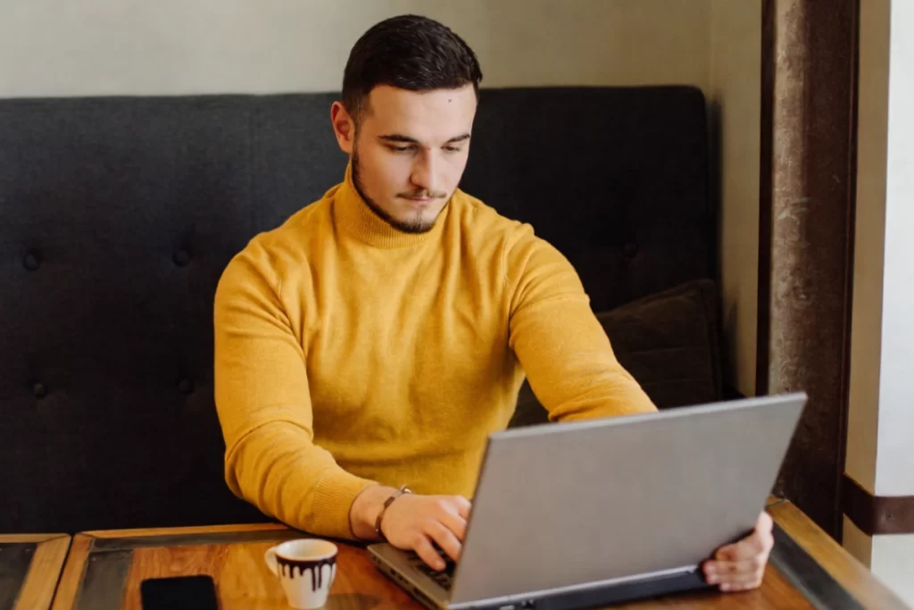 Homem sentado trabalhando em um notebook em ambiente home office representando: Transição da Reforma Tributária: checklist contábil, fiscal e financeiro para 2026.
