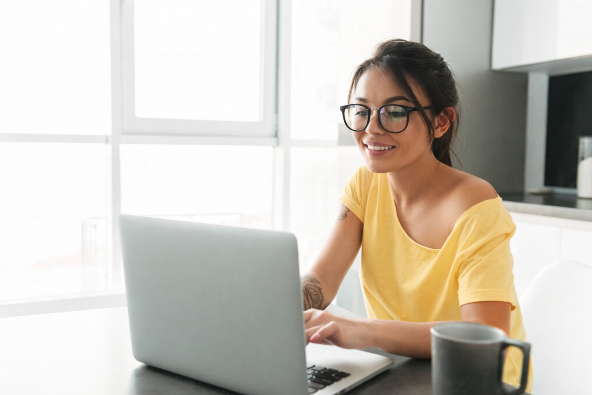 Mulher trabalhando em um notebook sobre uma mesa em ambiente de escritório representando: Escrituração Fiscal: Como mapear produtos e serviços para a Reforma Tributária sem comprometer a operação.