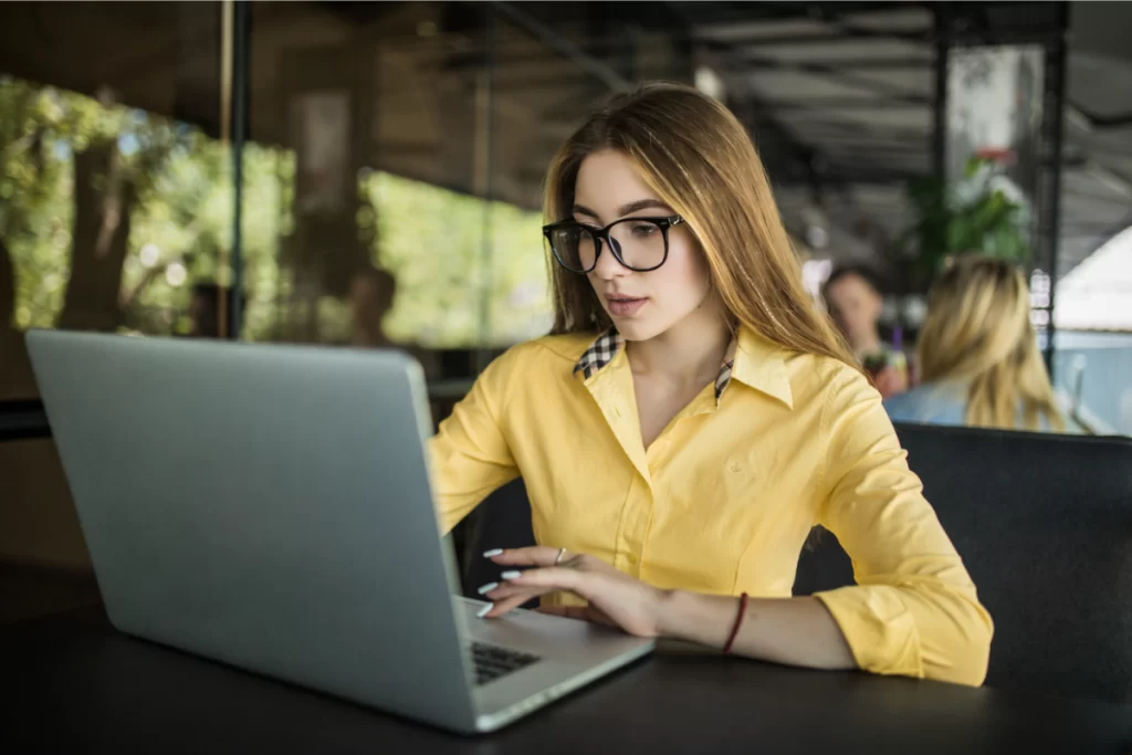 Mulher trabalhando em um notebook sobre uma mesa em ambiente de escritório representando: Simples Nacional na transição tributária: quando a gestão falha pode anular as vantagens do regime.
