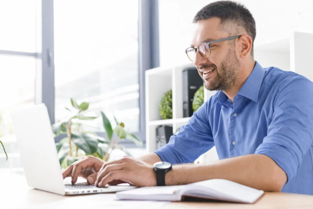 Homem sentado trabalhando em um notebook em ambiente home office representando: CFOP 6908: remessa de bem por conta de contrato de comodato e locação.