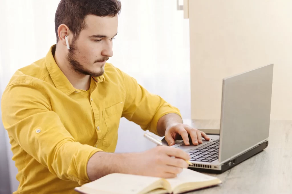 Homem sentado trabalhando em um notebook em ambiente home office representando: CFOP 5927: lançamento efetuado a título de baixa de estoque decorrente de perda, roubo ou deterioração.