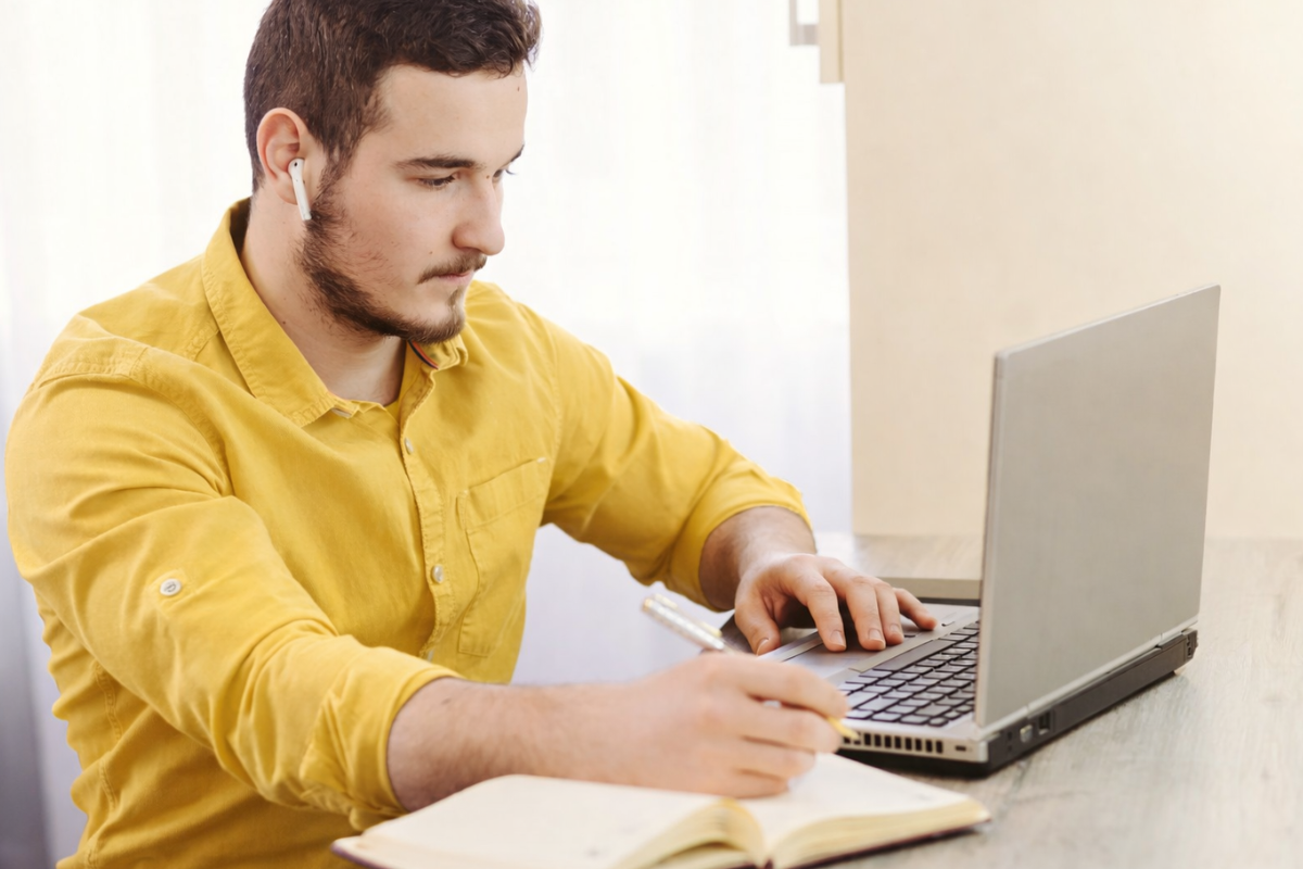 Homem sentado trabalhando em um notebook em ambiente home office representando: CFOP 5927: lançamento efetuado a título de baixa de estoque decorrente de perda, roubo ou deterioração.