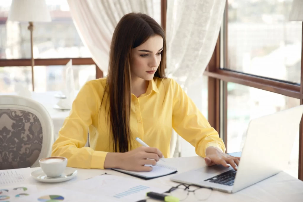 Mulher trabalhando em um notebook sobre uma mesa em ambiente de escritório representando: Diferença entre CFOP de venda, compra, devolução e remessa.