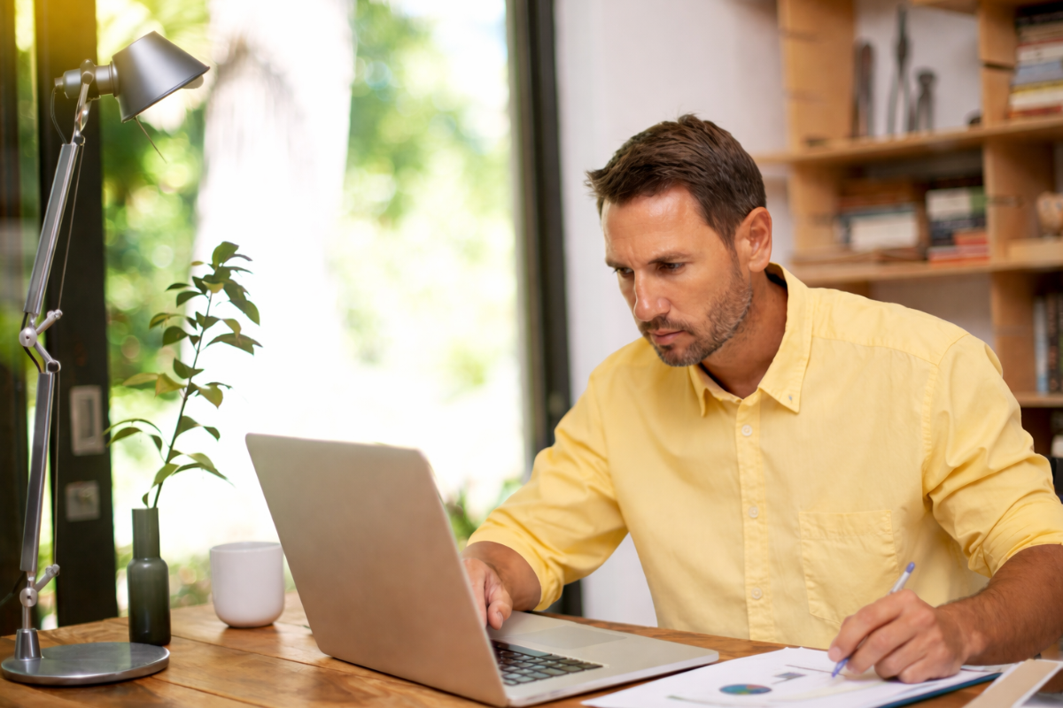 Homem sentado trabalhando em um notebook em ambiente home office representando: Indicadores contábeis que o empresário deveria acompanhar.