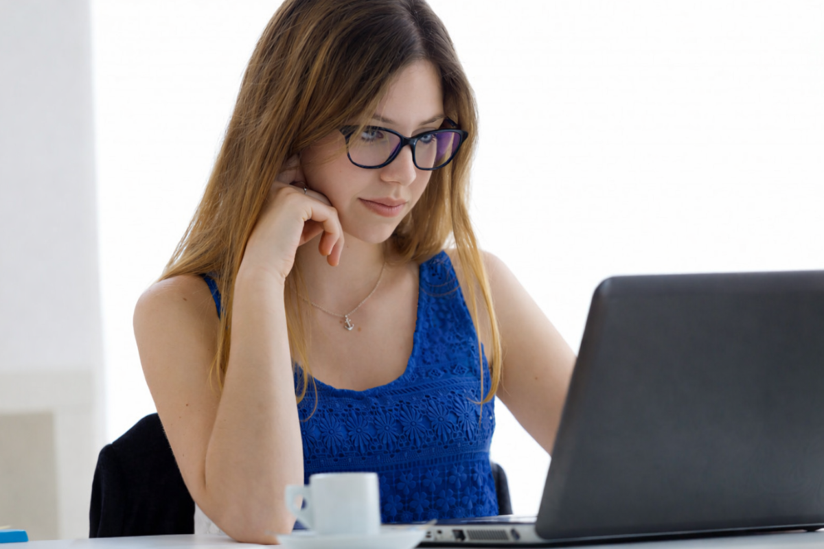 Mulher trabalhando em um notebook sobre uma mesa em ambiente de escritório representando: CFOP 6915: remessa de mercadoria ou bem para conserto ou reparo.