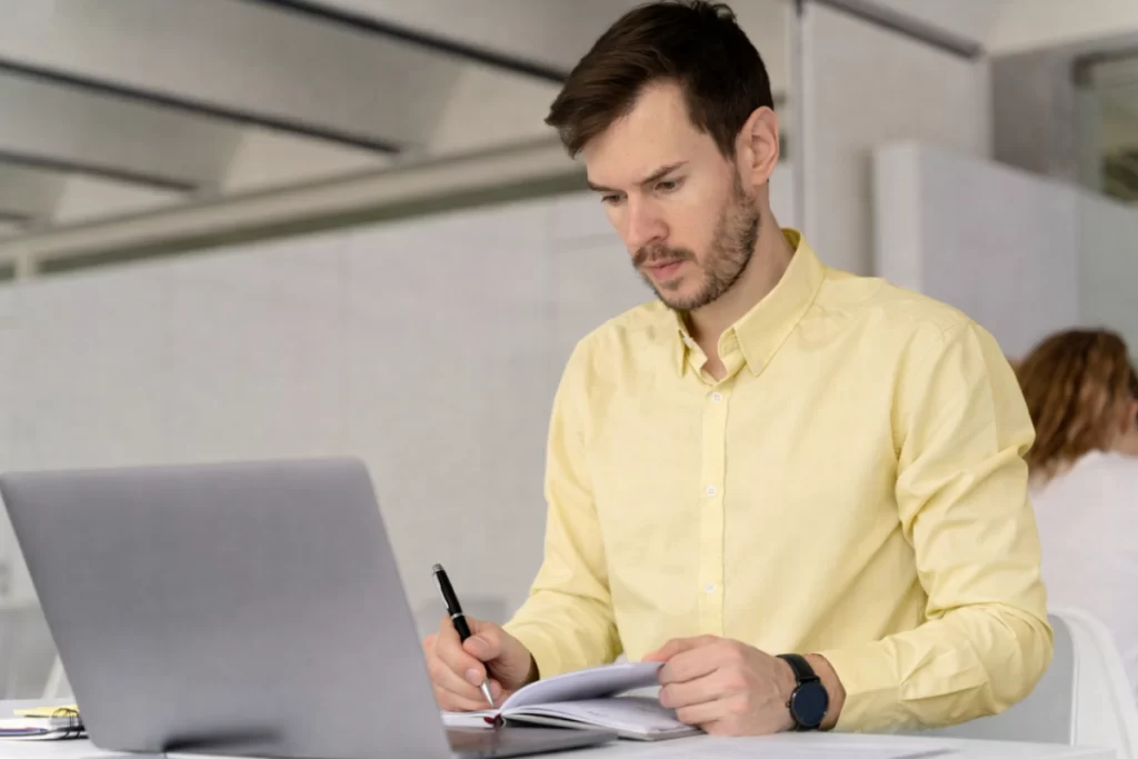 Homem sentado trabalhando em um notebook em ambiente home office representando: Códigos fiscais: como evitar erros na apuração de tributos na NF na Reforma Tributária.