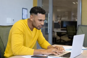 Homem sentado trabalhando em um notebook em ambiente home office representando: Prestador de serviço e Reforma Tributária: o guia completo.