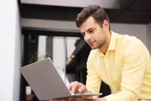 Homem sentado trabalhando em um notebook em ambiente home office representando: Tributação no destino: qual o verdadeiro impacto na venda interestadual.