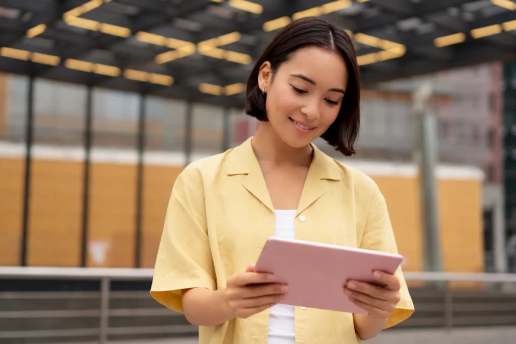 Mulher em pé com um tablet em mãos fazendo uso, em um armazém/fábrica representando: CFOP 2652: compra de combustível ou lubrificante para comercialização.