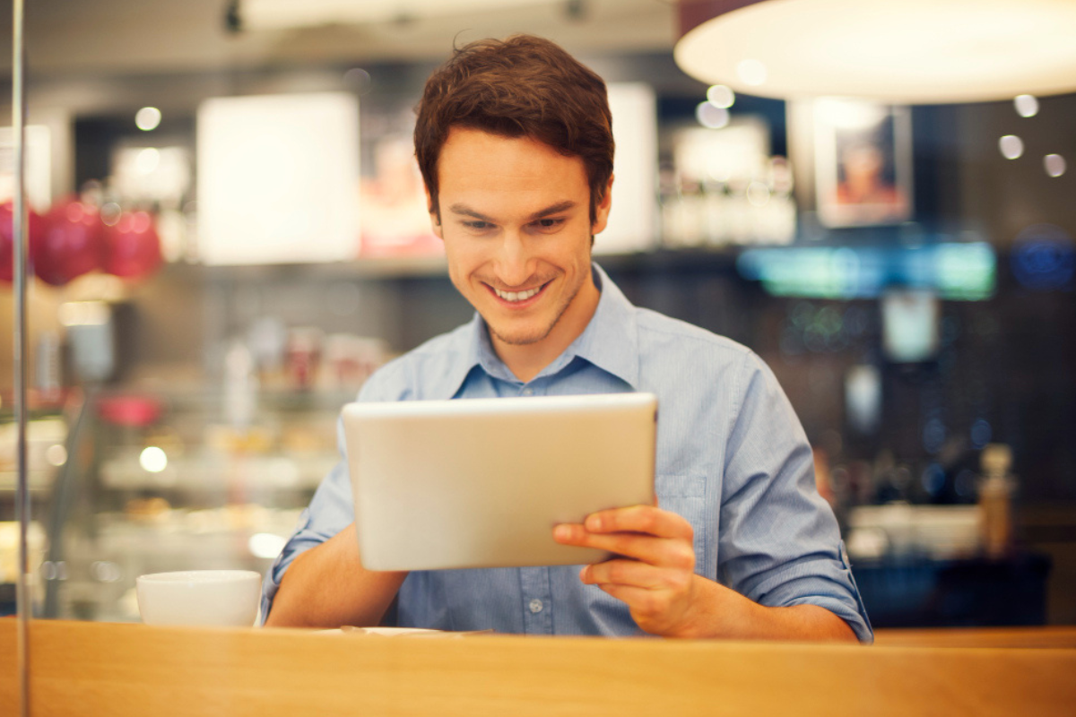 Homem em pé com um tablet em mãos fazendo uso, em um armazém/fábrica representando: CFOP 7102: venda de mercadoria adquirida ou recebida de terceiros.