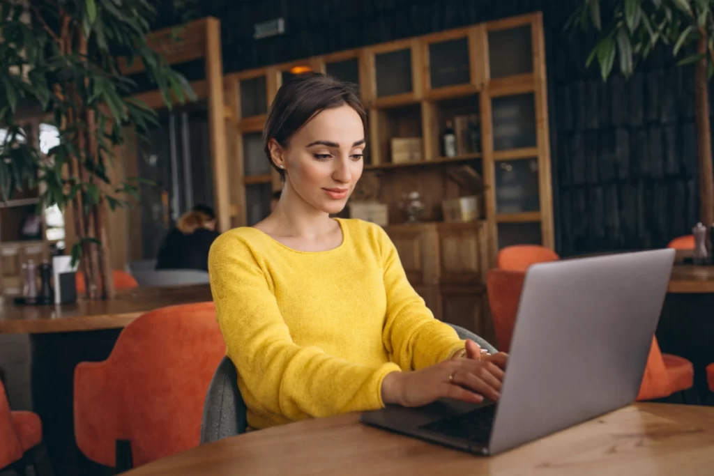 Mulher trabalhando em um notebook sobre uma mesa em ambiente de escritório representando: CFOP 6551: venda de bem do ativo imobilizado.