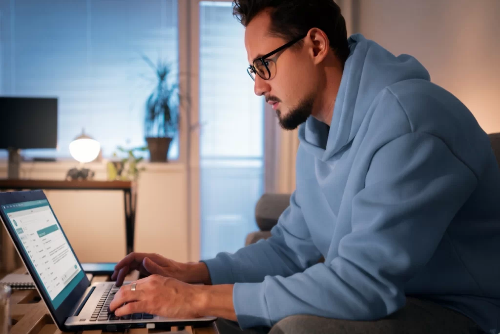 Homem sentado trabalhando em um notebook em ambiente home office representando: CFOP 2406: compra de bem para o ativo imobilizado cuja mercadoria está sujeita ao regime de substituição tributária.