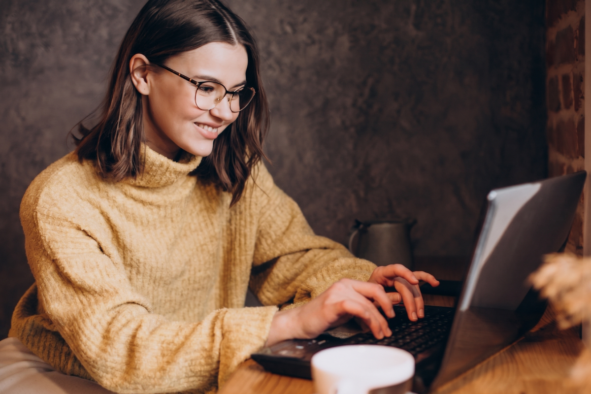 Mulher trabalhando em um notebook sobre uma mesa em ambiente de escritório representando: CFOP 5922: lançamento efetuado a título de simples faturamento decorrente de venda para entrega futura.