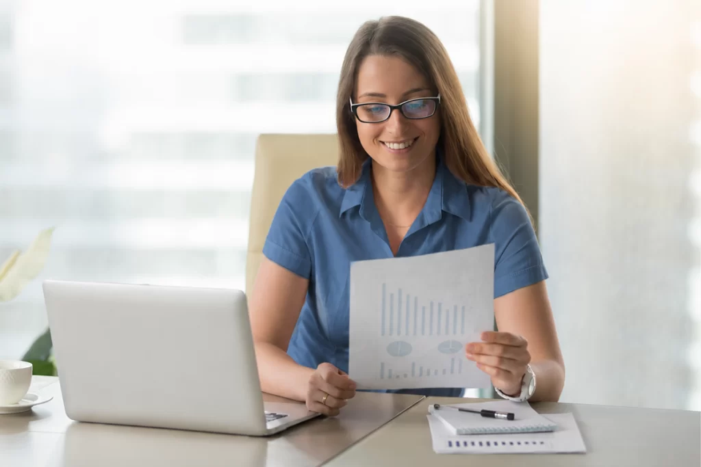 Mulher trabalhando em um notebook sobre uma mesa em ambiente de escritório representando: Rejeição 528: Valor do ICMS difere do produto BC e Alíquota.