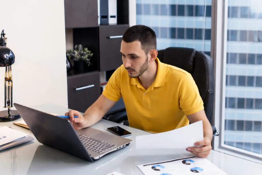 Homem sentado trabalhando em um notebook em ambiente home office representando: Multas por erro de CFOP: quando cabe defesa administrativa?