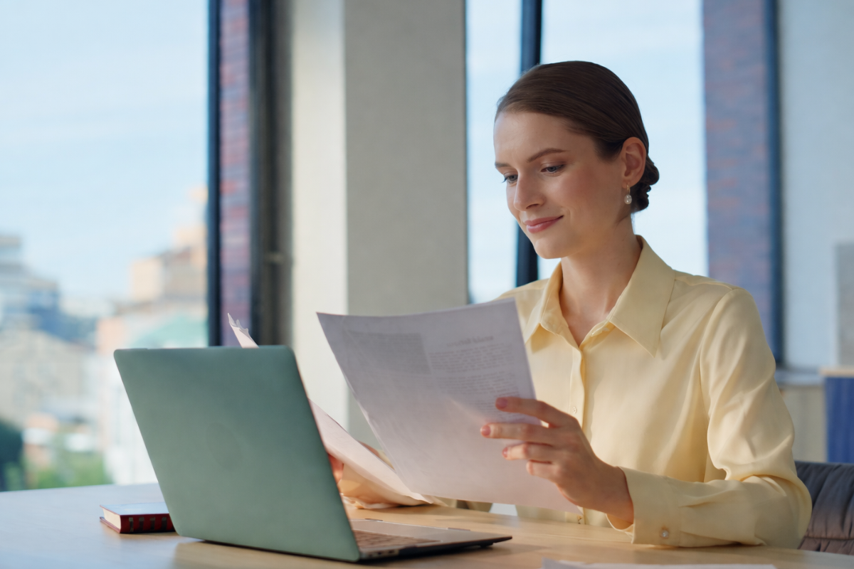 Mulher trabalhando em um notebook sobre uma mesa em ambiente de escritório representando: Como documentar correções de notas para fins de fiscalização.